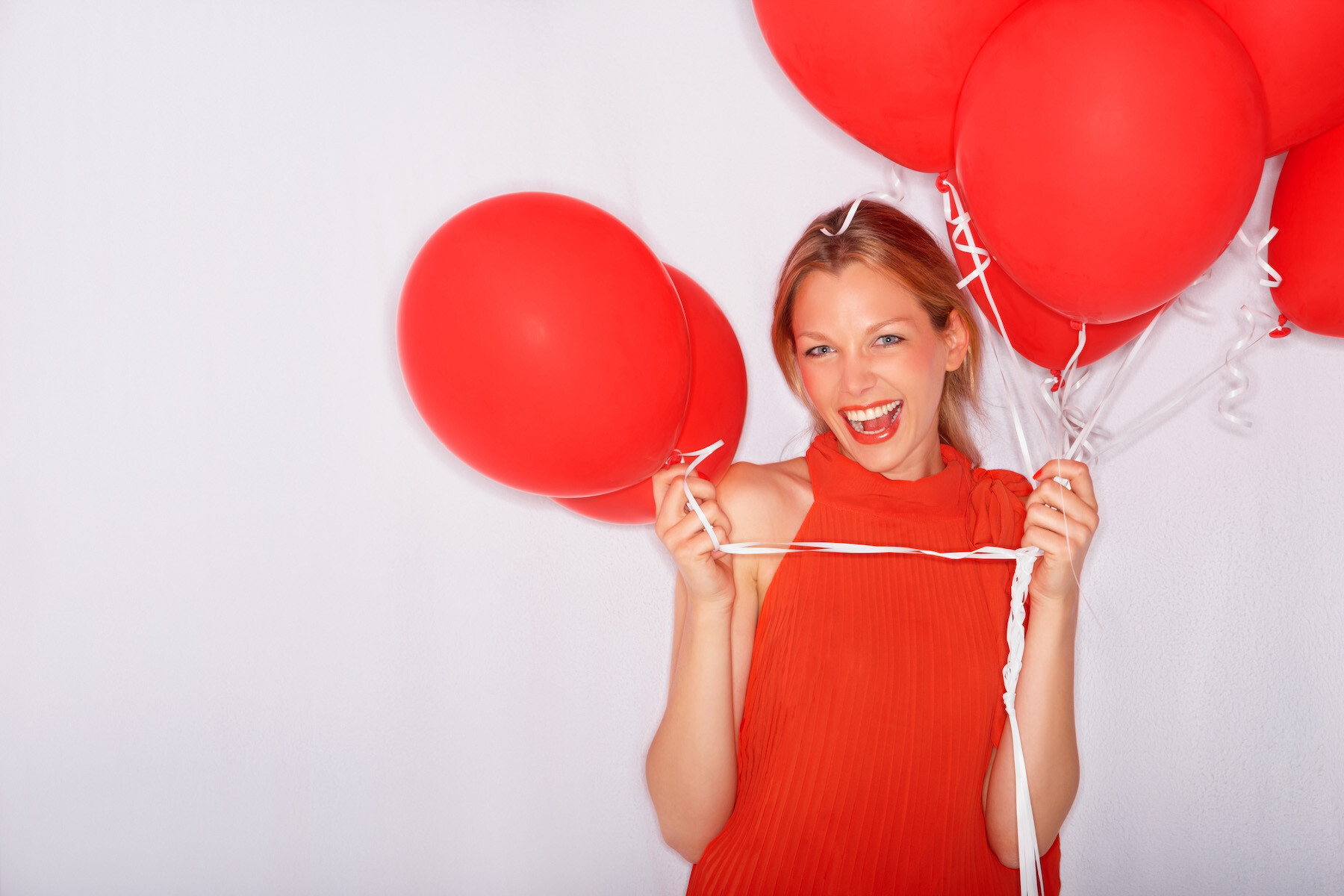 Excited esthetician woman holding red balloons